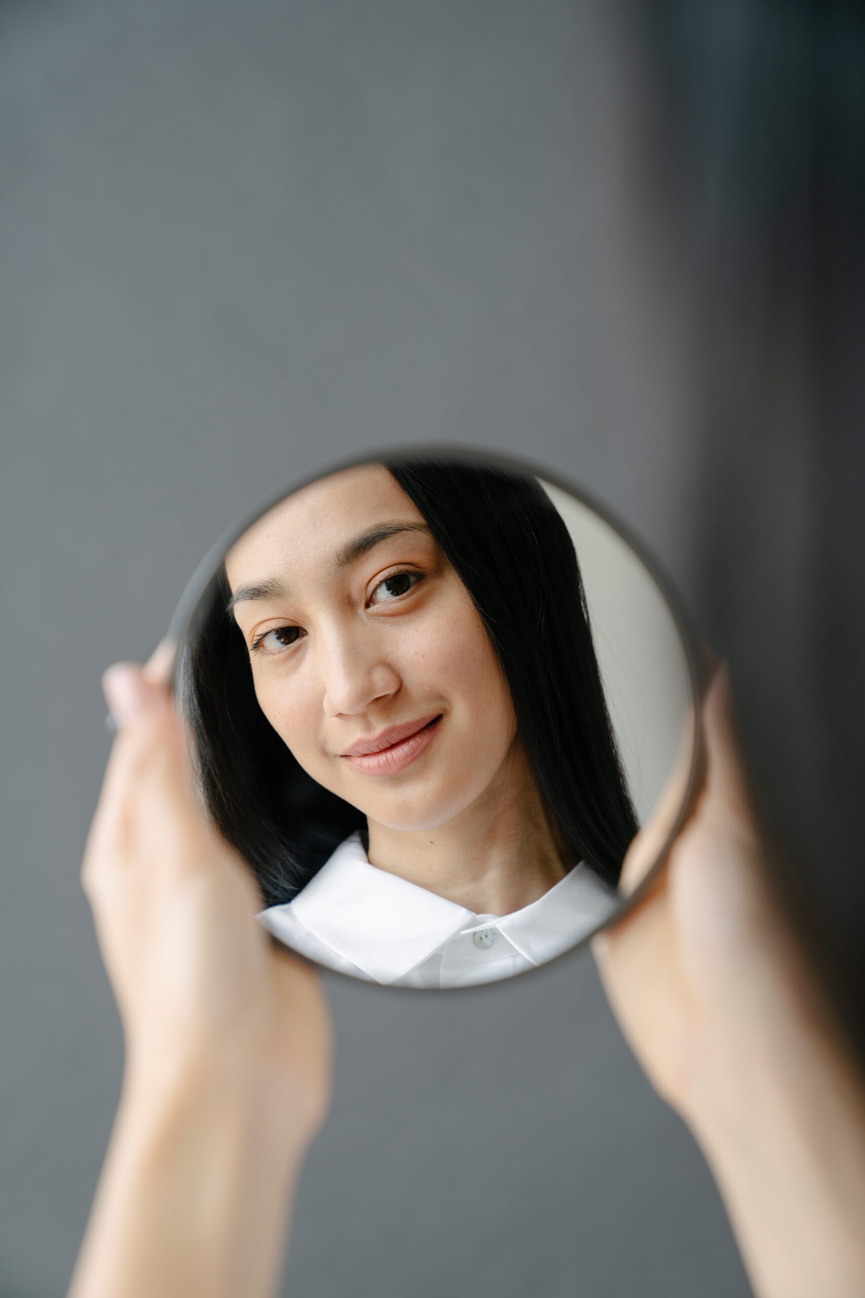 Woman smiling and looking into a mirror.